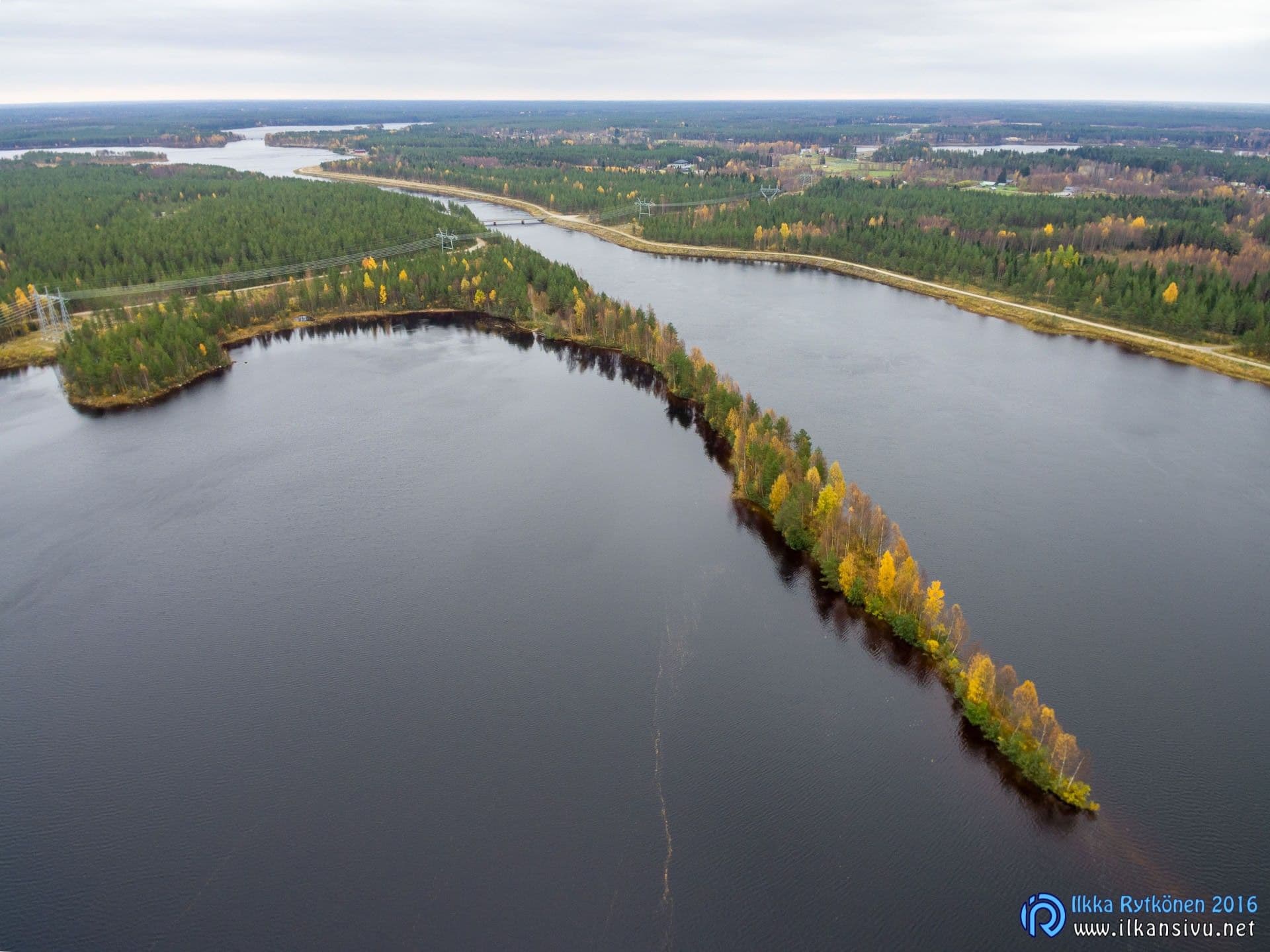 Aerial view of a narrow wooded island in a broad river