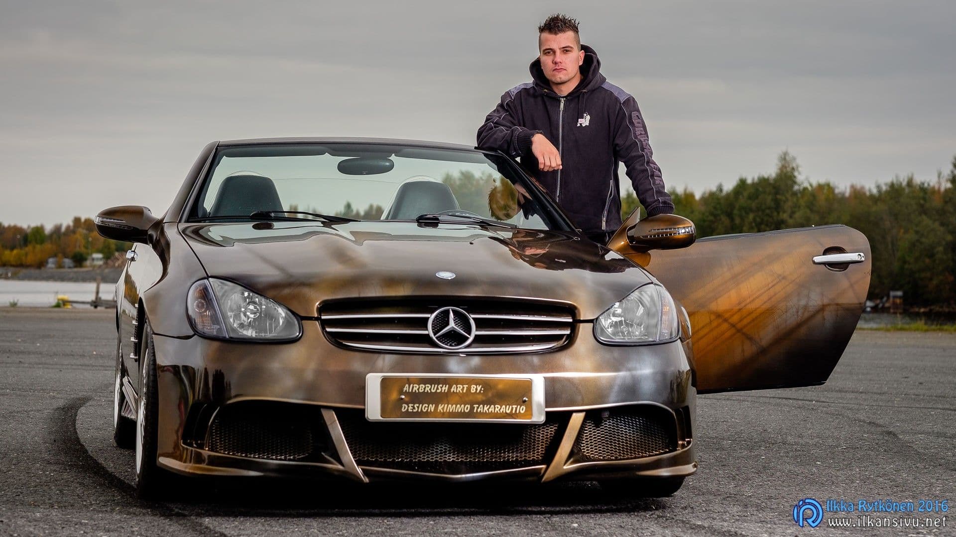 Mies seisoo Mercedes-avoauton avoimen oven vieressä