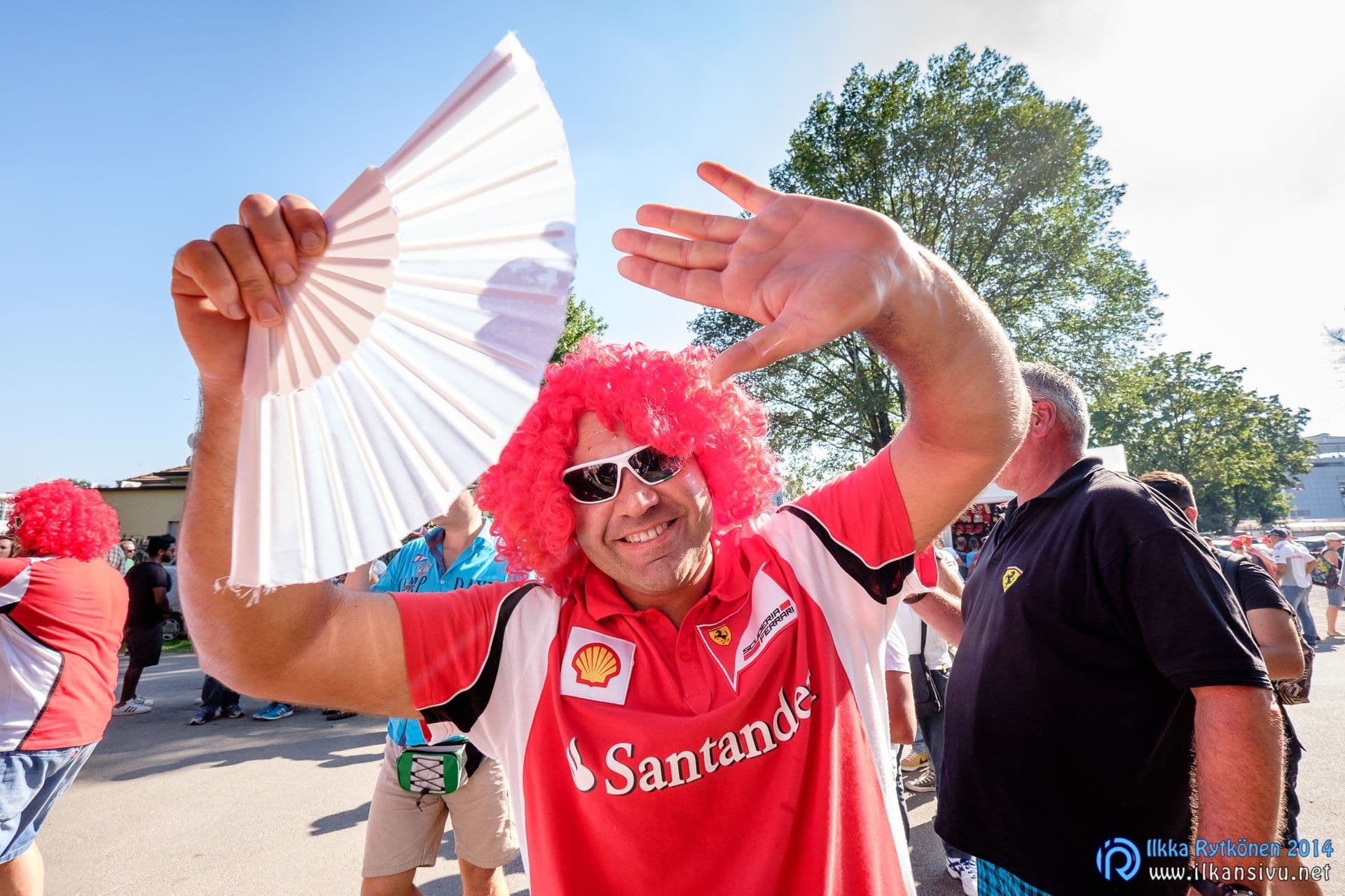 Punaperuukkinen Ferrari-kannattaja heiluttaa viuhkaa ja kättään