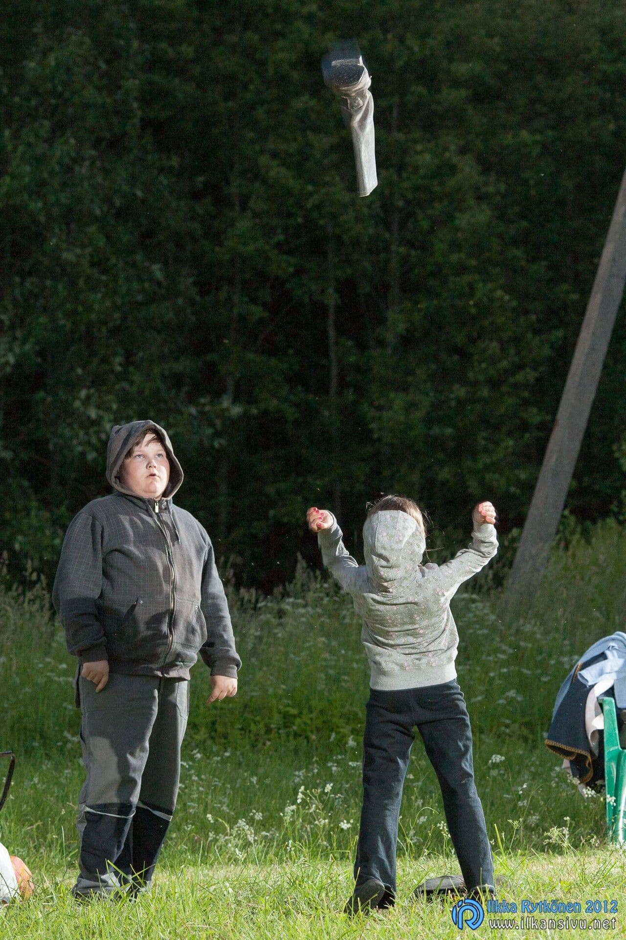 Kaksi ihmistä heittää esineen ilmaan nurmikolla